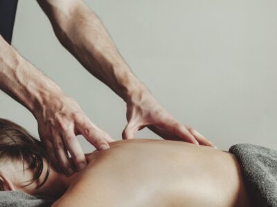 A masseur gives a professional sports massage to a young female athlete in a massage room